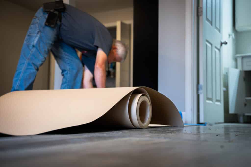 Dusty laying down protective floor covering for a bathroom remodel.